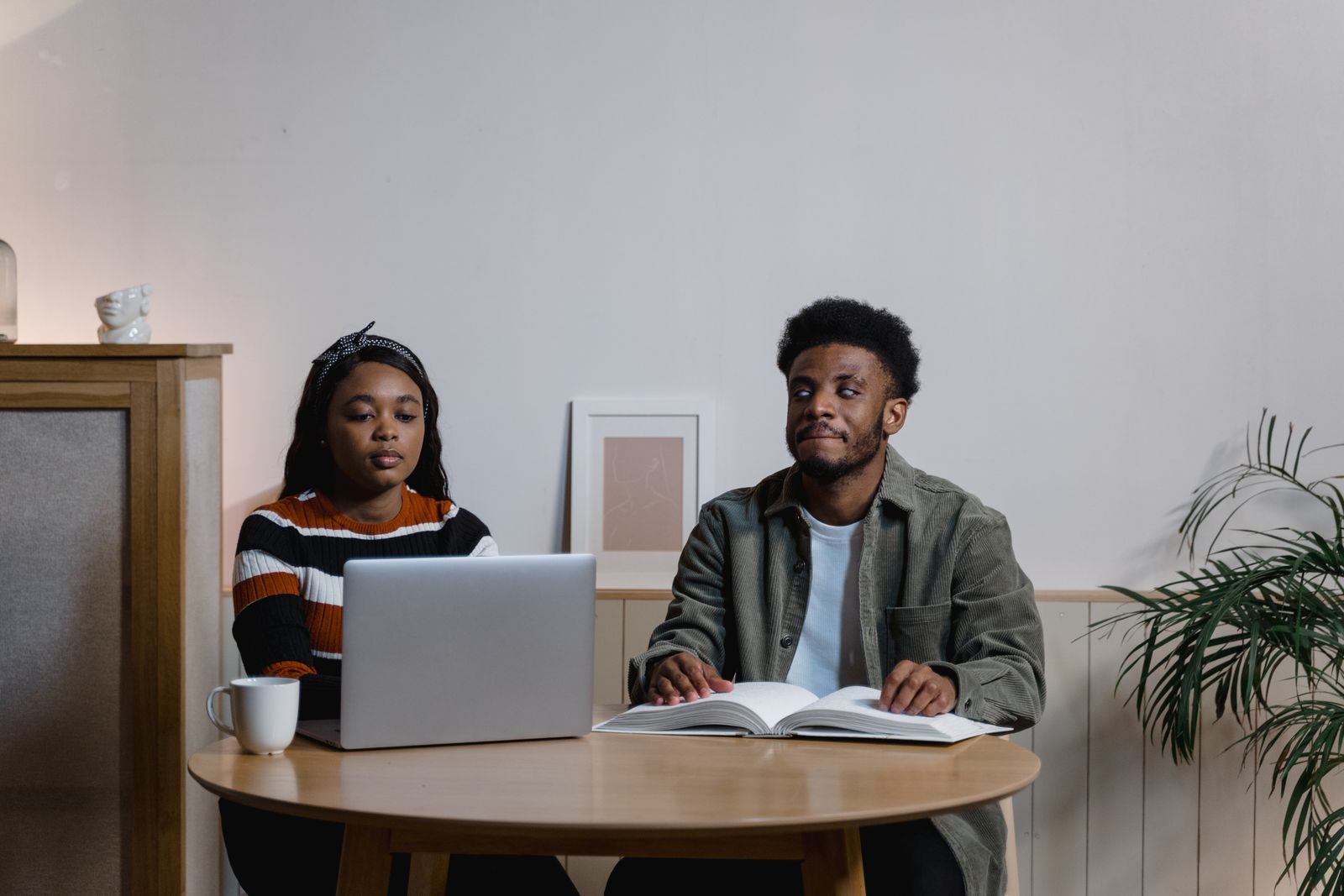 Two young adults work together using a laptop and Braille materials.